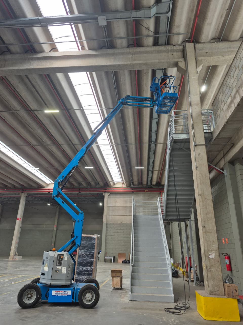 Técnico da CI Tecnologia em plataforma elevatória articulada passando infraestrutura de rede no galpão da Atual Cargas